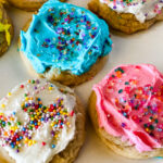 Close up of frosted sugar cookies on a white plate.