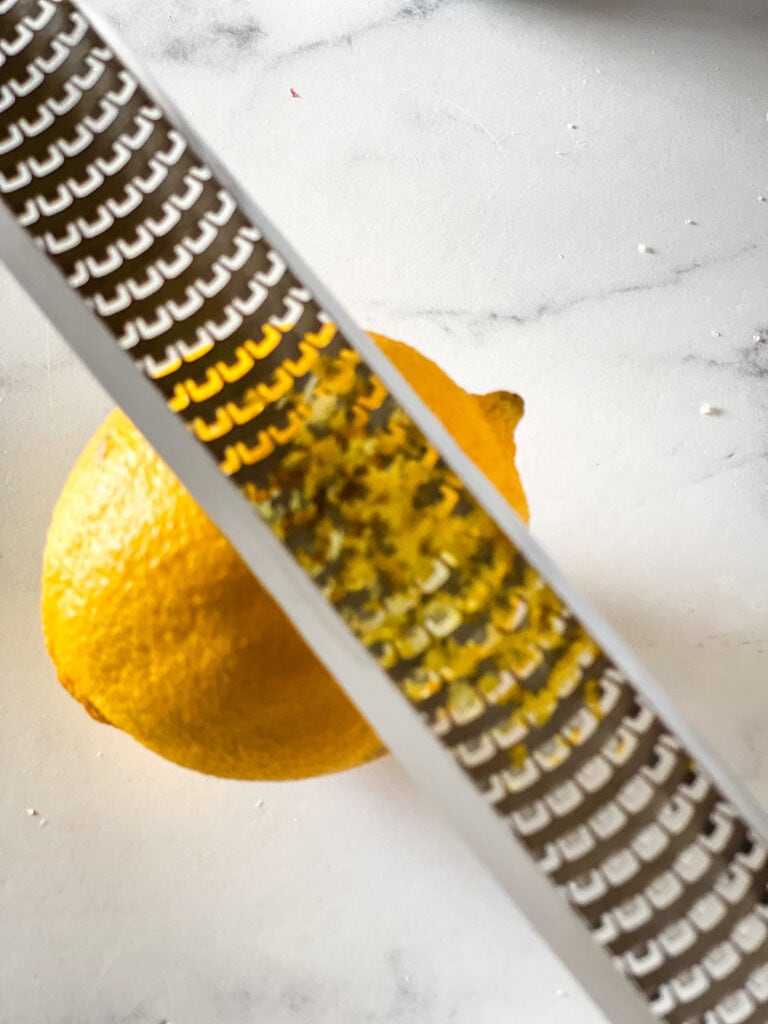 Grating lemon zest with a lemon zester.