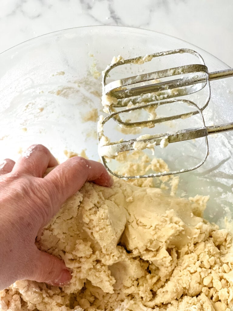 Bringing together the mixed dough by hand.