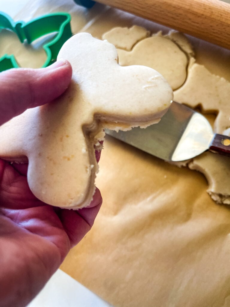 Lifting the butterfly shaped cutout cookie with a spatula. The dough has warmed and so the cookie did not cut and lift out as cleanly. The bits around the edges will need to be removed or the cookie recut.
