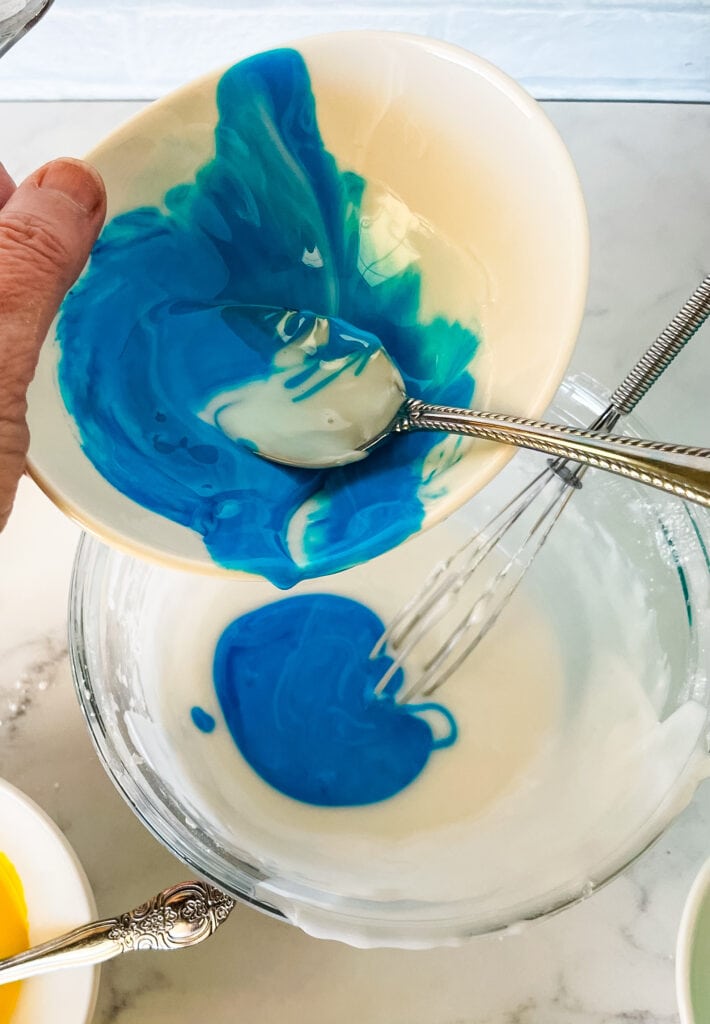 Mixing overcolored blue icing with white icing.