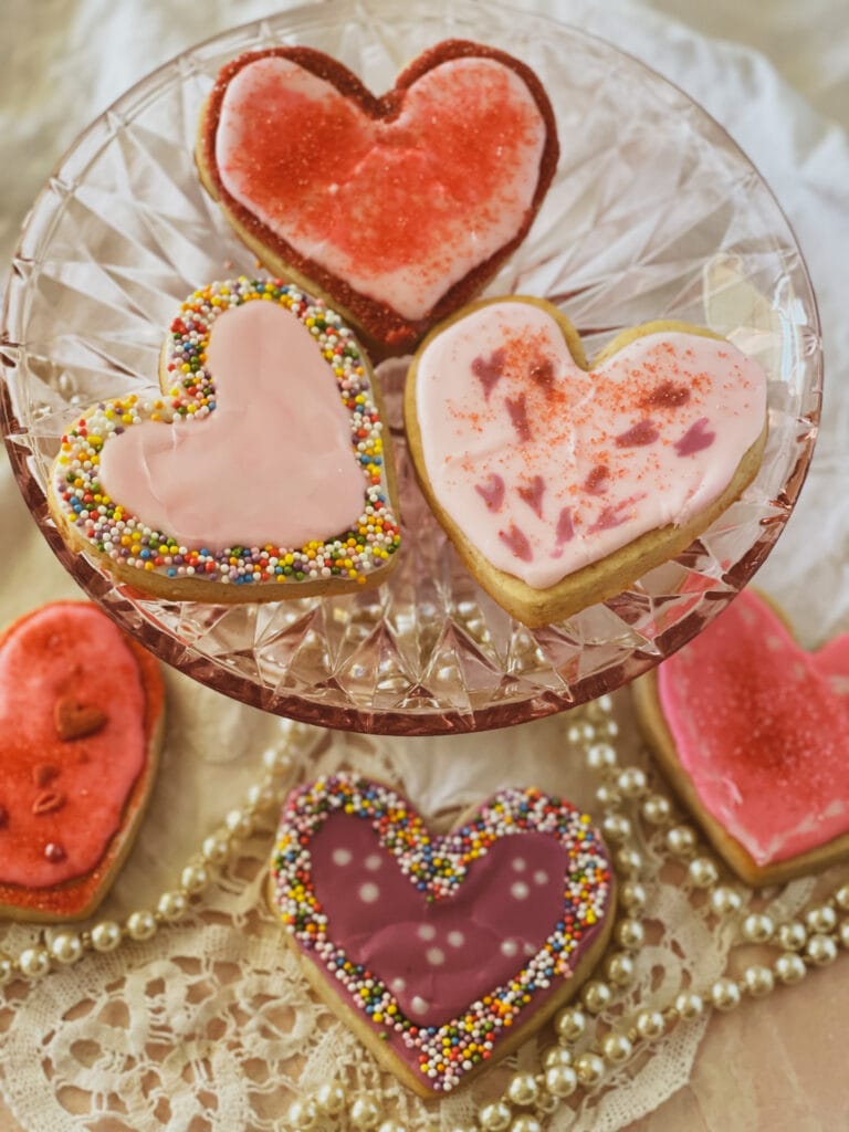 A plate of three iced valentines cookies with three more under it.