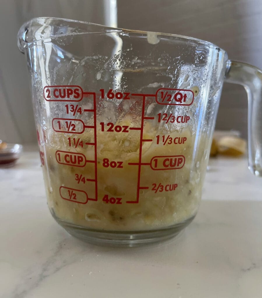 Mashing the bananas into a glass measuring cup to ensure accurate measurement.