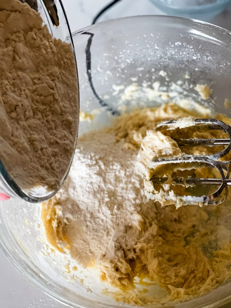 Adding half of the flour mixture to the wet ingredients for lemon cookies.