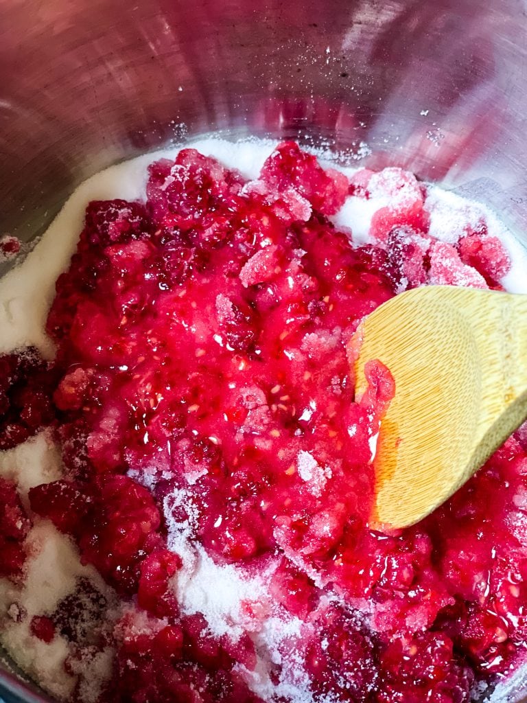 Stirring and mashing the raspberries into the sugar as the jam is beginning to cook.