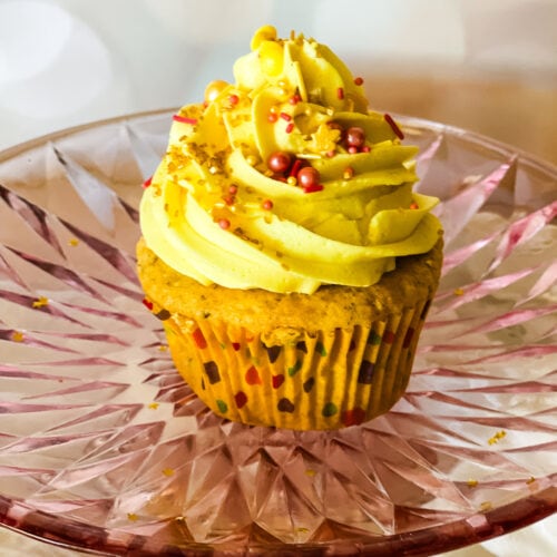 Cupcake with vegan lemon frosting on a pink glass plate.