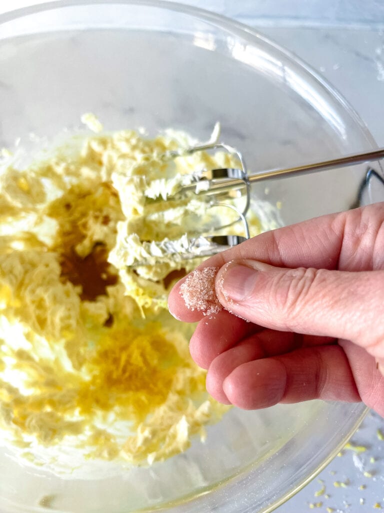 Adding a generous pinch of salt to the lemon frosting.