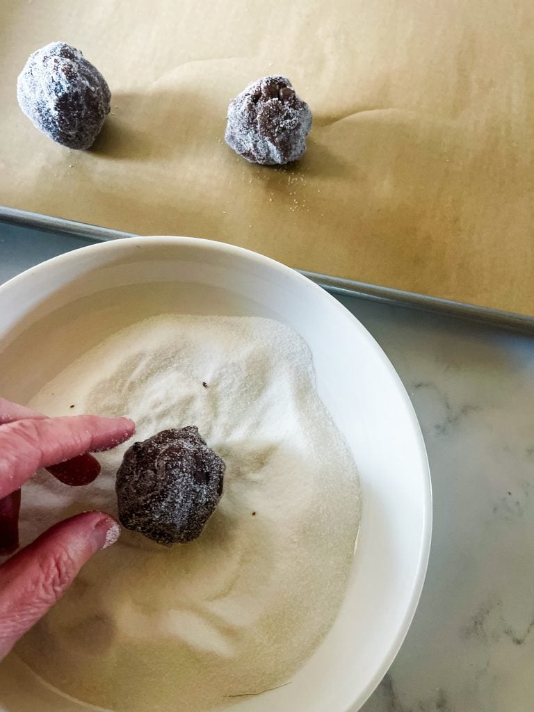 Rolling the chocolate peanut butter cookie dough ball into sugar.