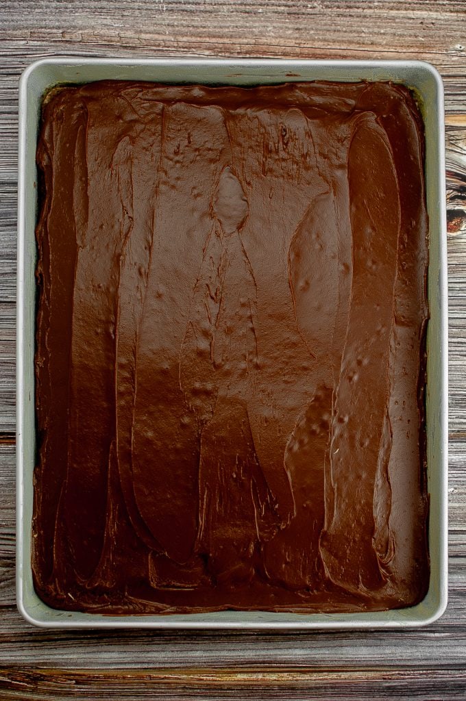 The chocolate frosting is spread on the chocolate cake.