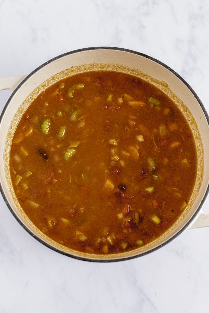pumpkin chili ingredients simmering in a white pot showcasing healthy veggie ingredients.