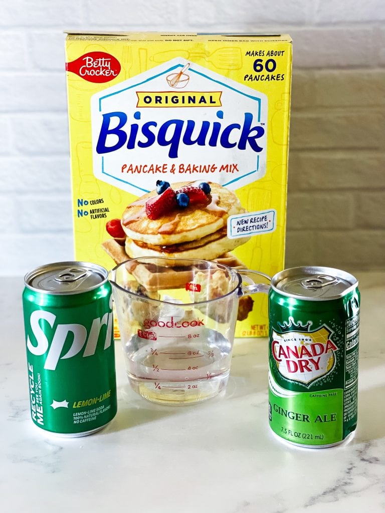 Box of Bisquick mix, measuring cup of water, can of sprite on the left, can of ginger ale on the right