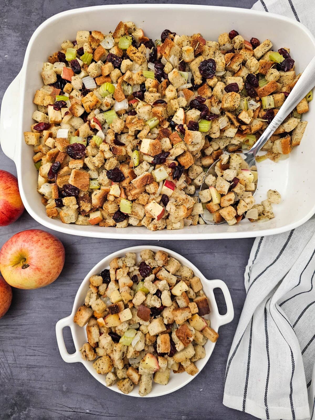 Vegan stuffing with apples and cranberries for healthy eating. In a casserole dish with a large spoon an small rounds dish. Apples on the side.