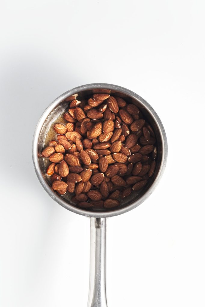 Almonds in a pan with the maple syrup ready to cook.