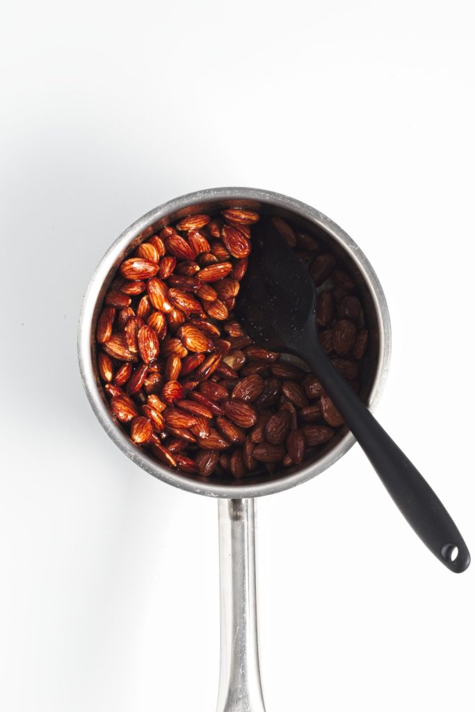 Cooking the almonds in maple syrup to coat.