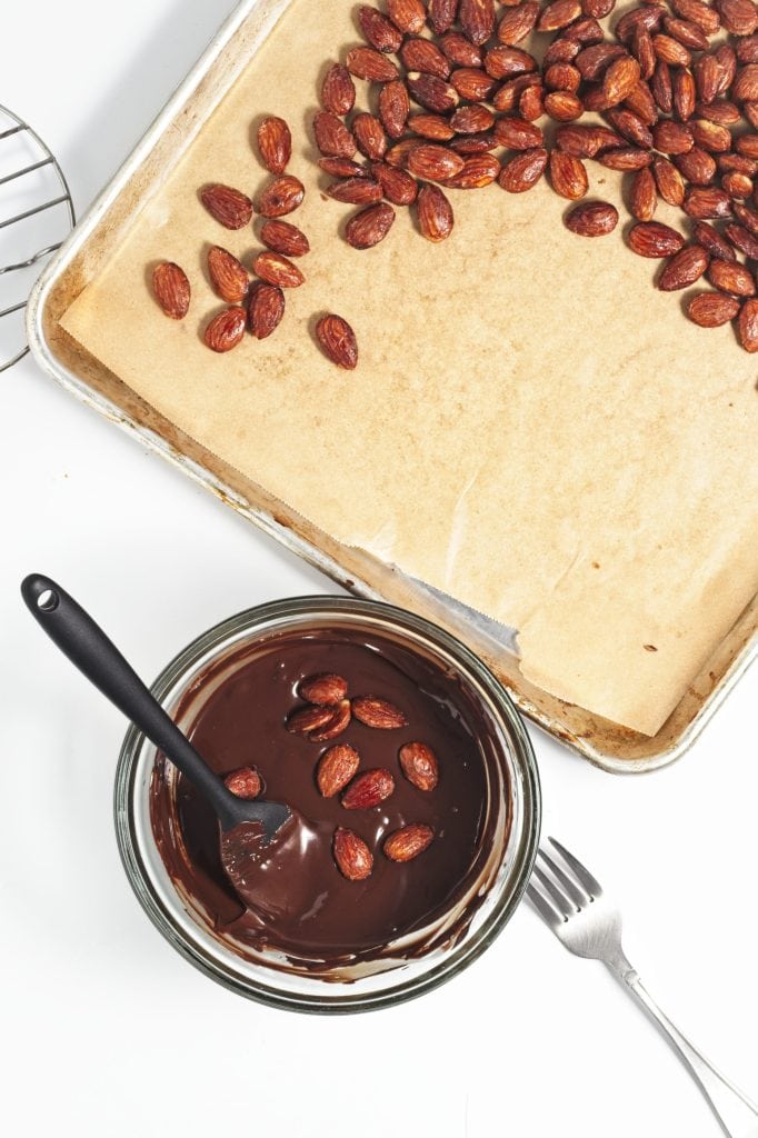 Coating the almonds with chocolate a few at a time.