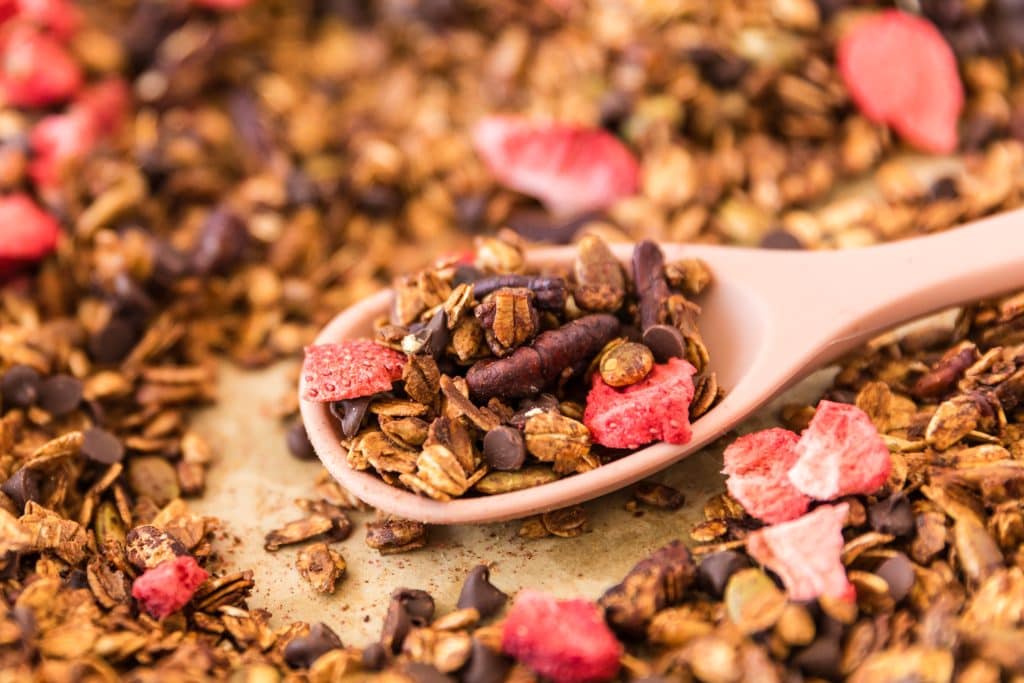 a spoonful of chocolate strawberry granola scooped on the sheet pan.