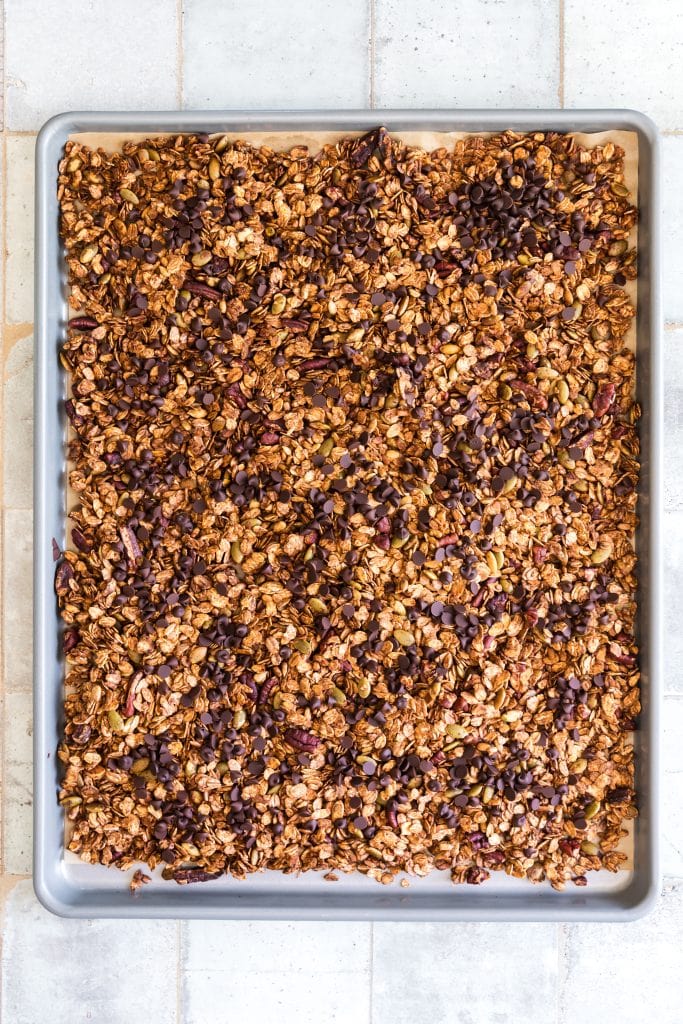 strawberry granola on the pan with the chocolate chips mixed in waiting for the dehydrated strawberries