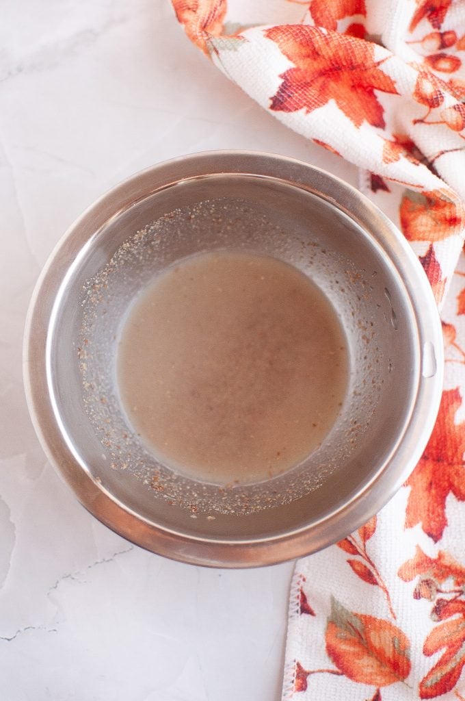Making a flax egg in a metal bowl with a fall leaf napkin on the right.