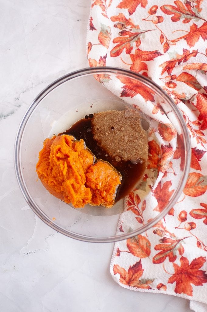 Wet ingredients for vegan pumpkin cookies in a clear bowl with a fall napkin on the right.