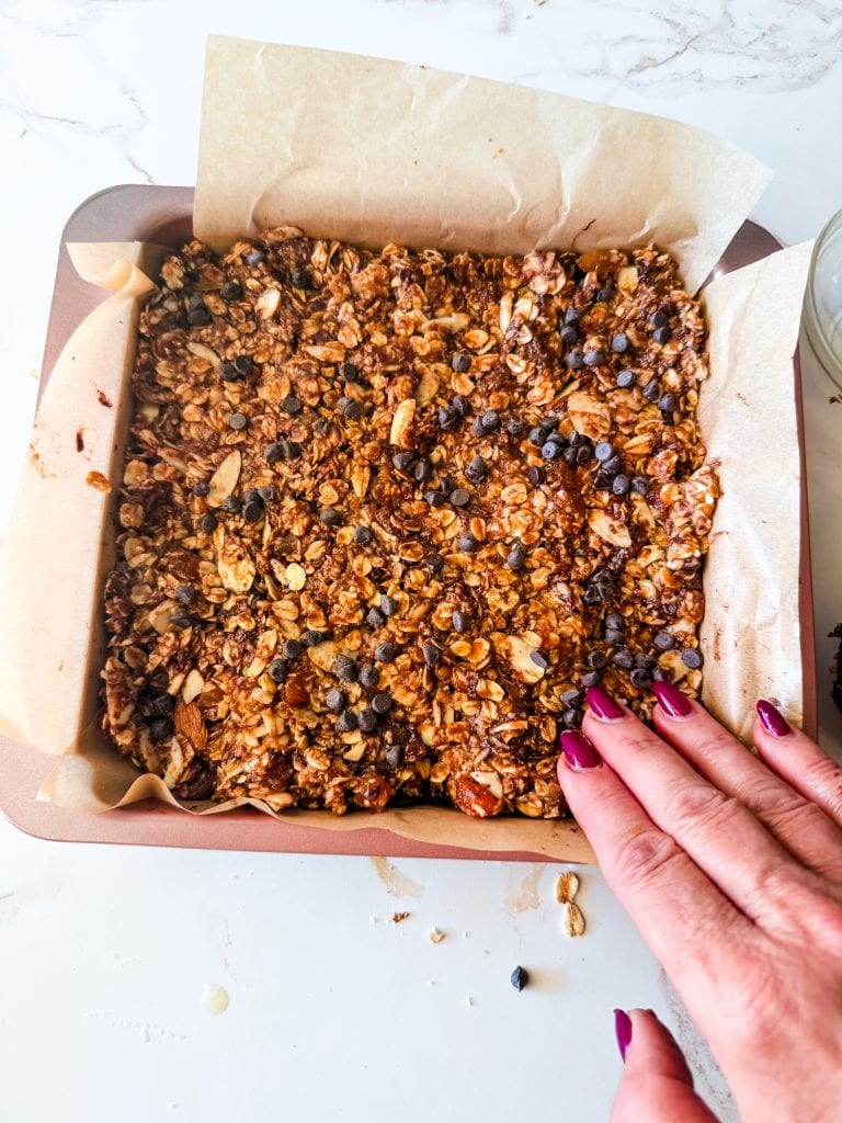 pressing the chocolate chips into the top of the almond butter granola bars in the pan