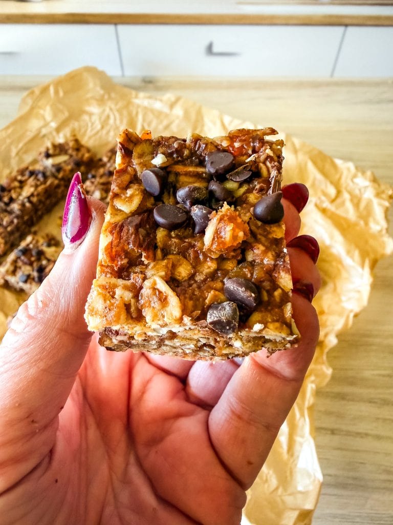 Chocolate chip granola bar with nuts and oats, hand-held for a healthy snack.