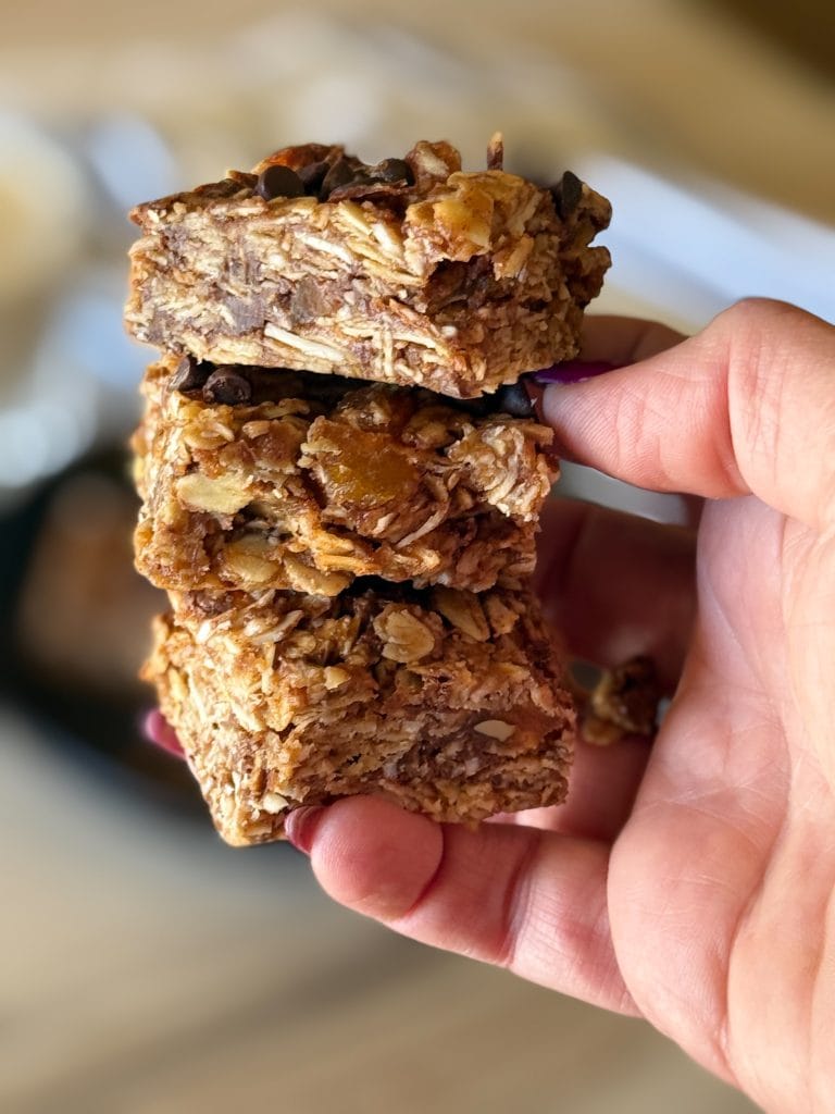 Holding three almond butter granola bars in hand