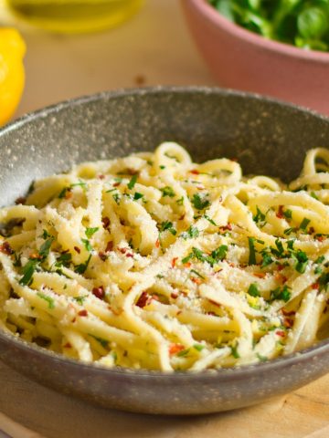Creamy veggie pasta served in a skillet with fresh herbs and grated vegan parmesan cheese on top. Perfect for a healthy vegan meal.