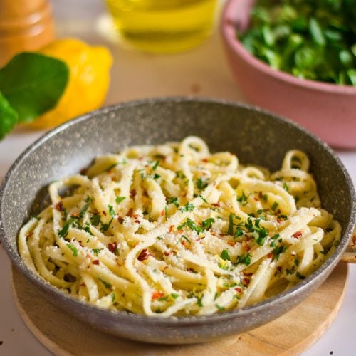 Creamy veggie pasta served in a skillet with fresh herbs and grated vegan parmesan cheese on top. Perfect for a healthy vegan meal.