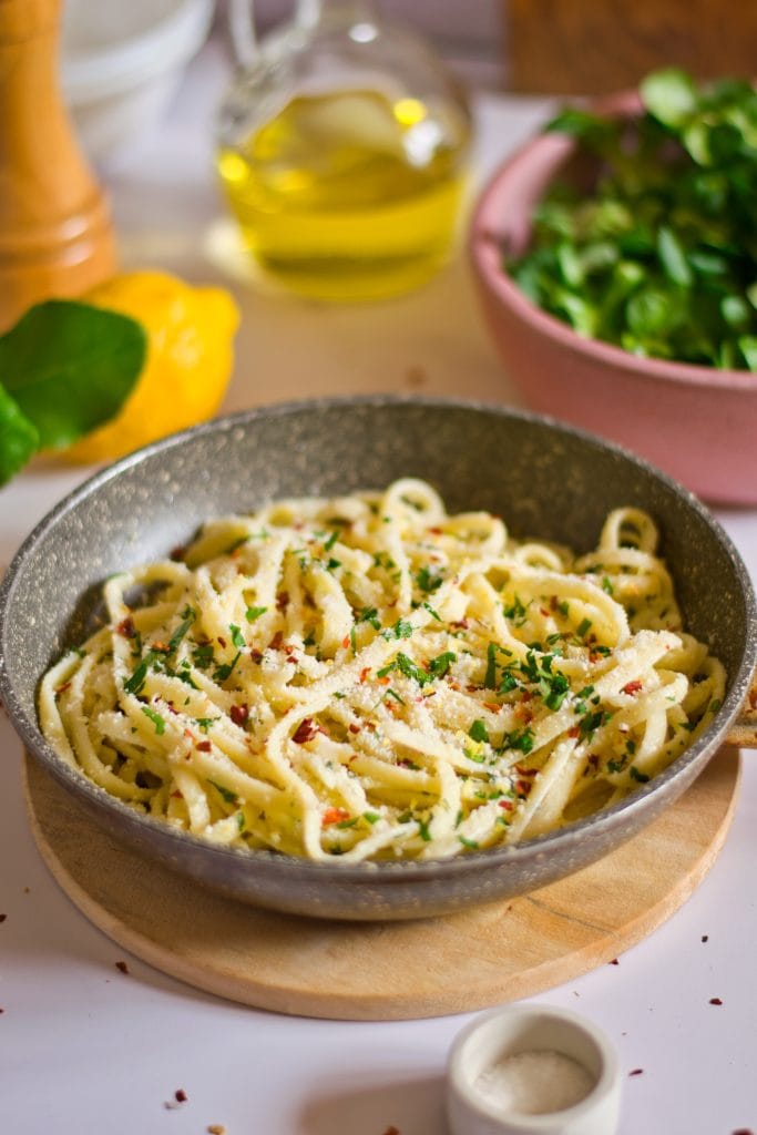 Creamy veggie pasta served in a skillet with fresh herbs and grated vegan parmesan cheese on top. Perfect for a healthy vegan meal.