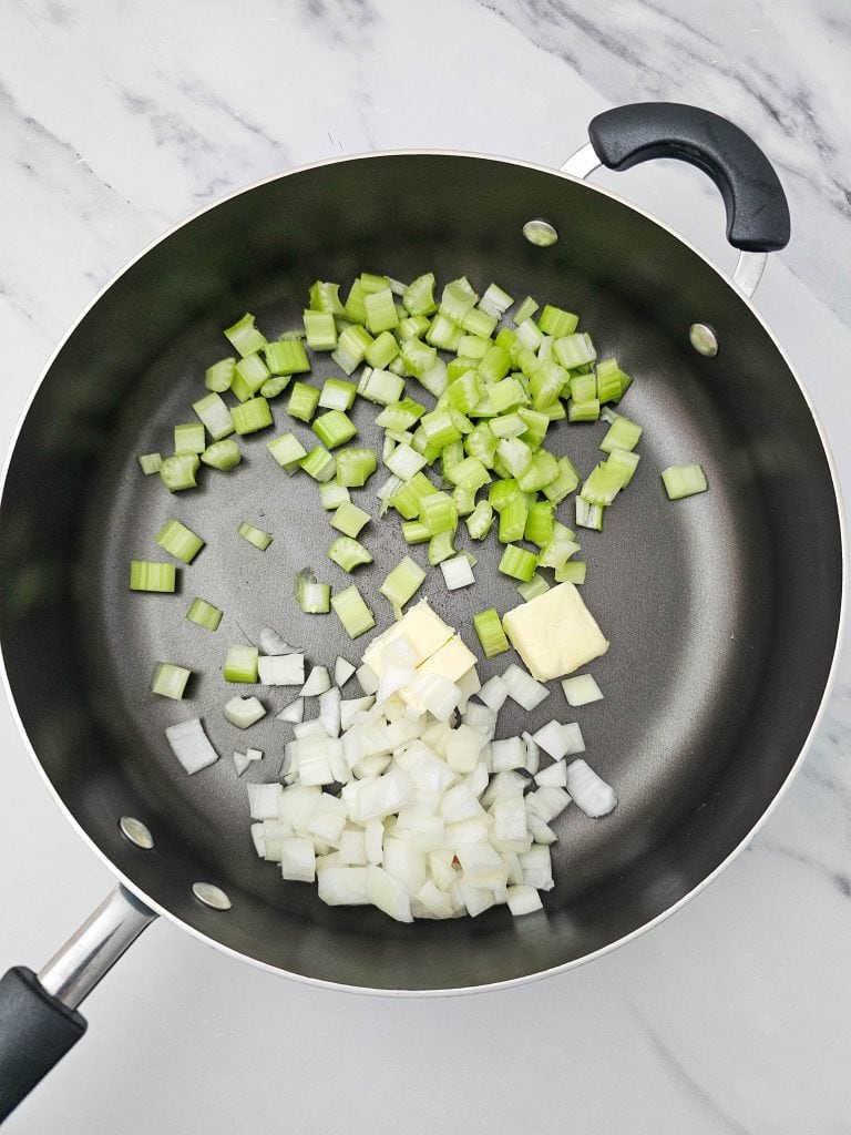 Sautéing the chopped celery and apples in a fry pan with vegan butter.