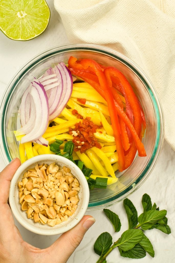 Colorful vegetable salad with sliced onions, red bell peppers, yellow mango, and chopped nuts. Perf.